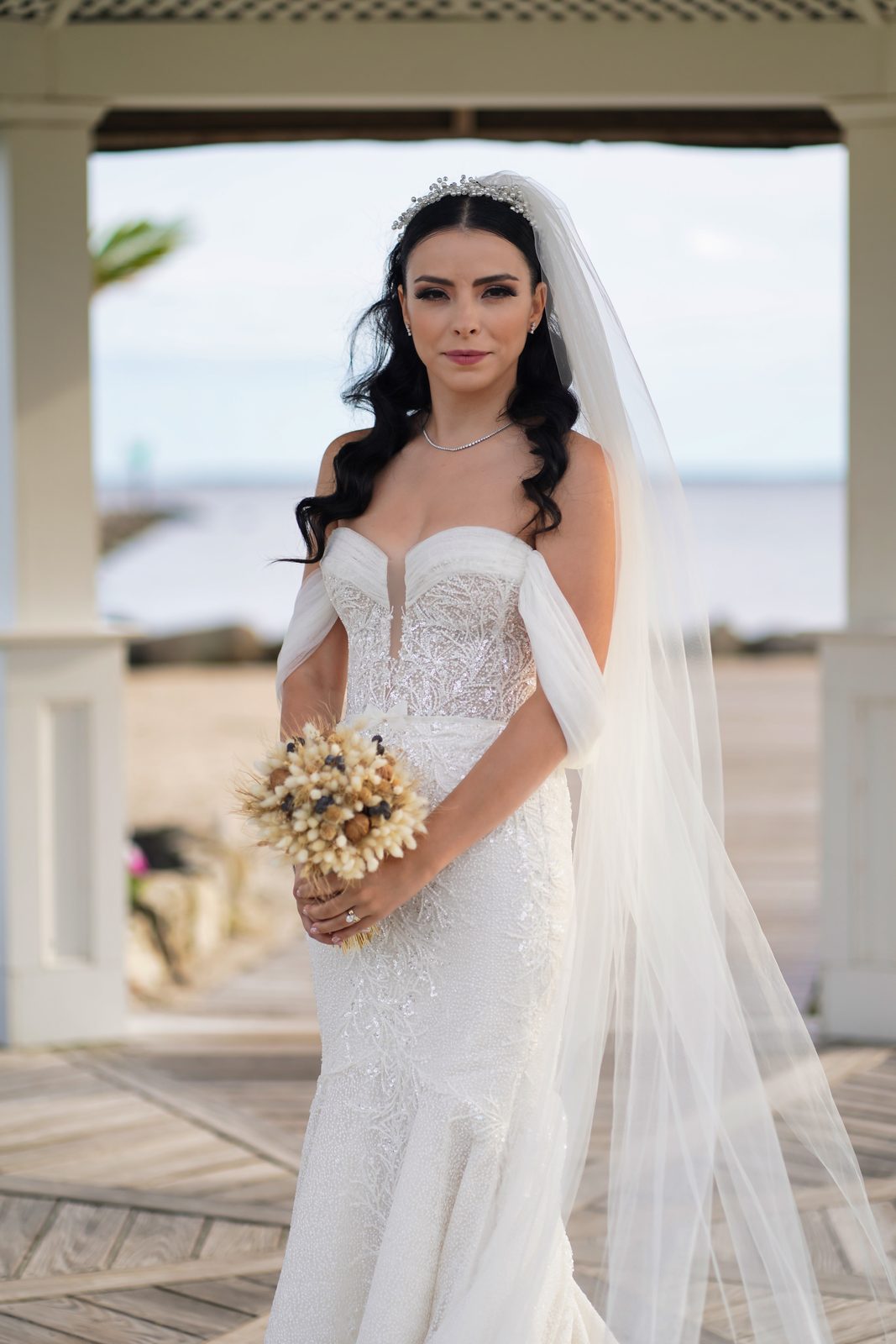 Bride with bouquet under a waterfront gazebo