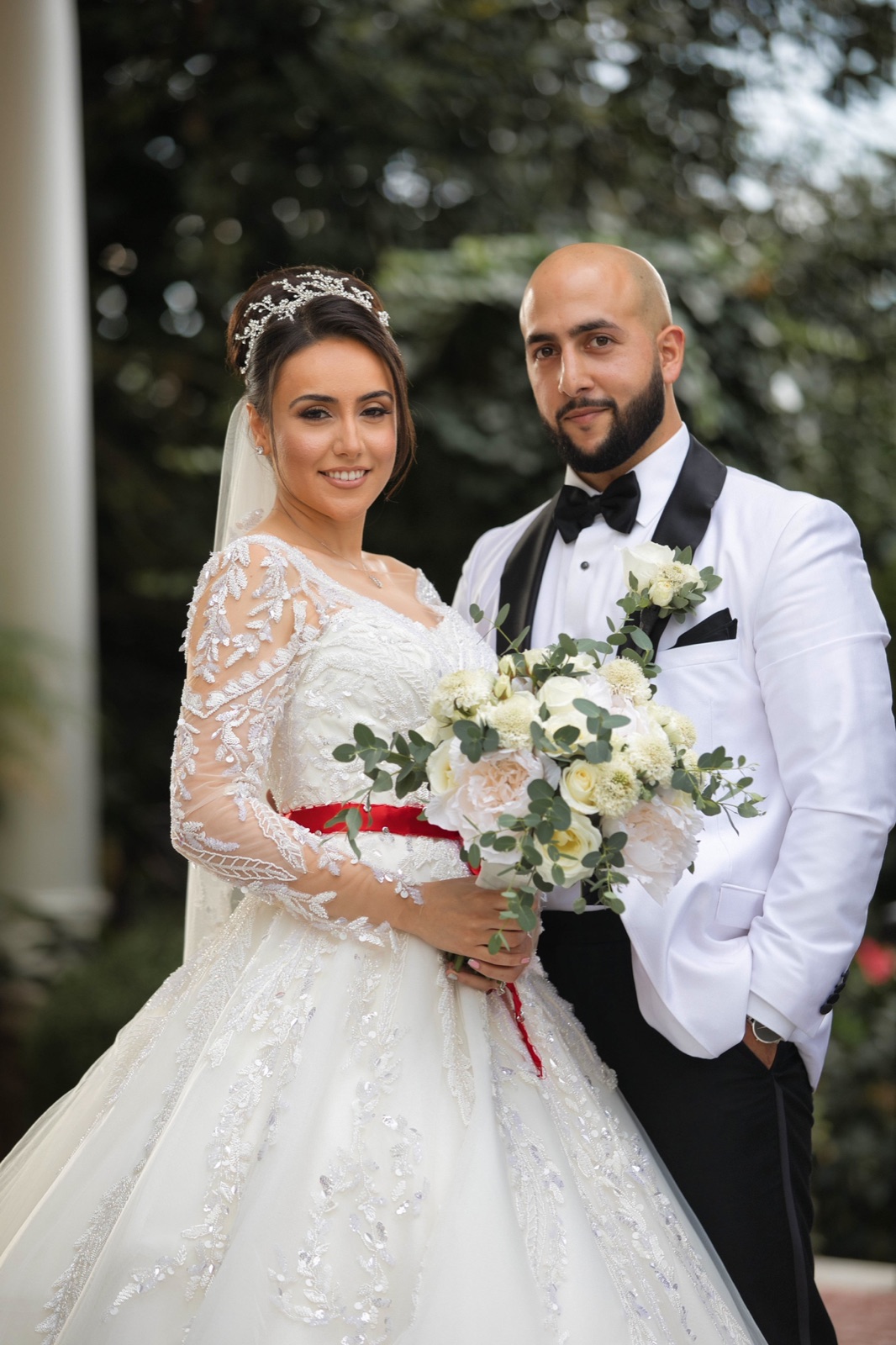 Bride and groom portrait under the trees, bride with a red sash