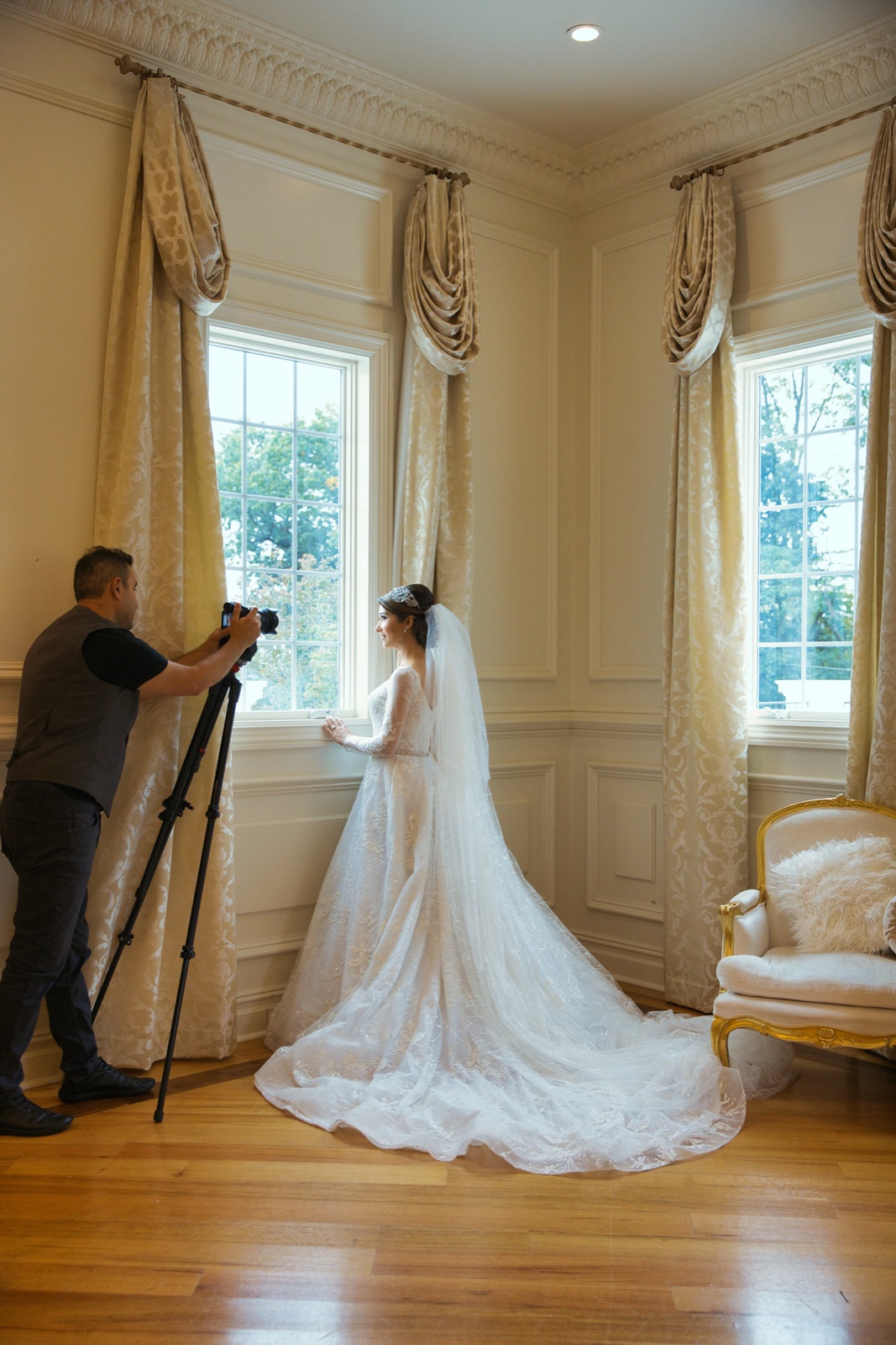 Photographer capturing the bride by tall windows in an elegant suite