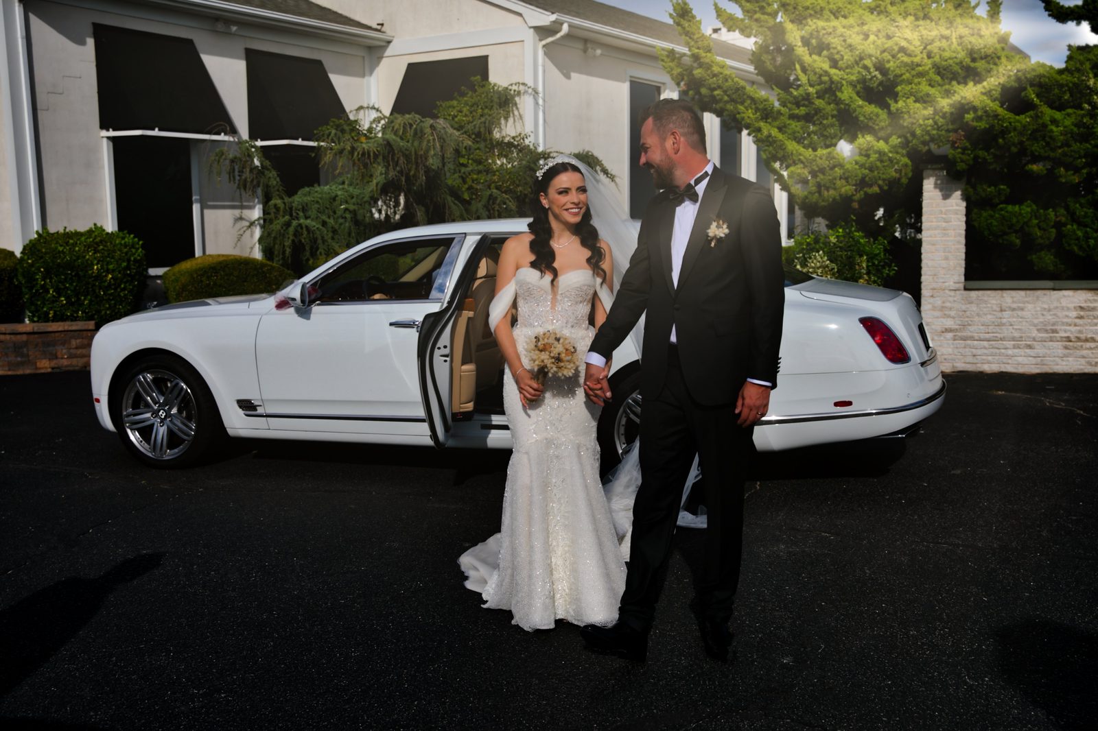 Bride and groom beside a white Bentley